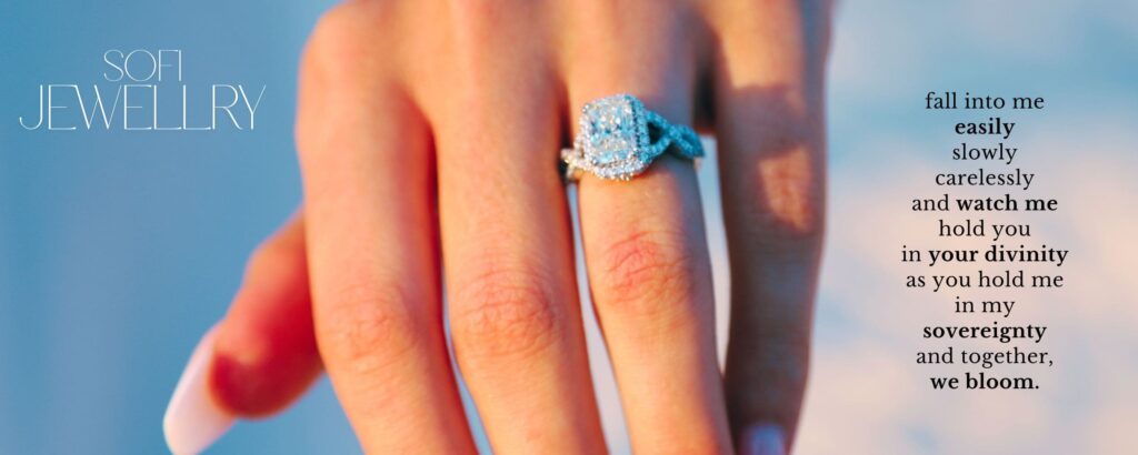 A close up shot of a females hand with a large, silver diamond ring on her engagement finger, advertising jewellery for a brand called 'Sofi Jewellery' with the poem 'fall into me easily slowly carelessly and watch me hold you in your divinity as you hold me in my sovereignty and together, we bloom.'